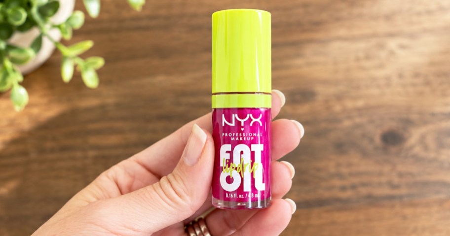 hand holding a bright green and pink tube of NYX Fat Oil Lip Drip