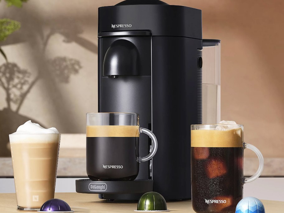 black nespresso machine on counter with three cups of coffee
