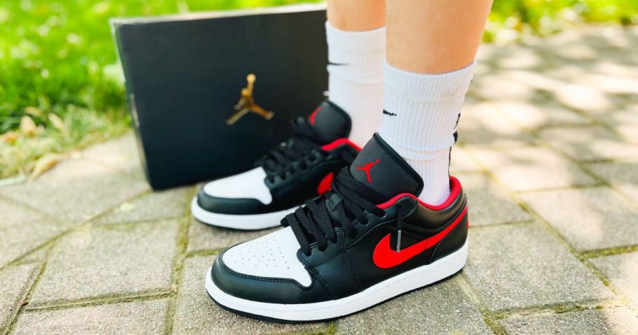 Child's feet wearing Nike Jordan shoes while standing next to a Nike shoebox