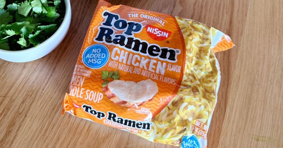 A pack of Nissin Chicken Flavor Top Ramen next to a bowl of Cilantro