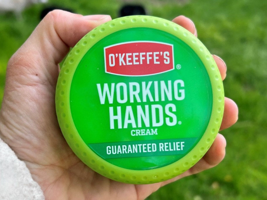 hand holding a container of O'Keeffe's Working Hands Hand Cream