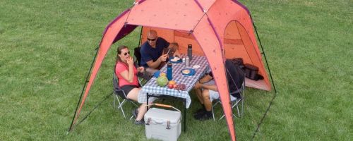 4 people sitting at a picnic table underneath a beach tent