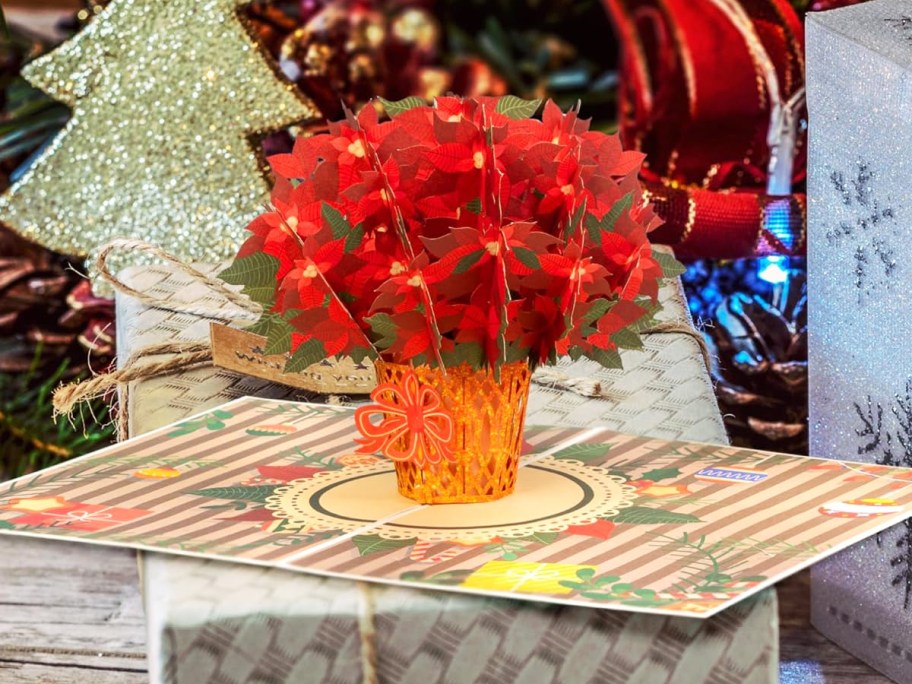 red poinsettia pop-up card on top of a gift box