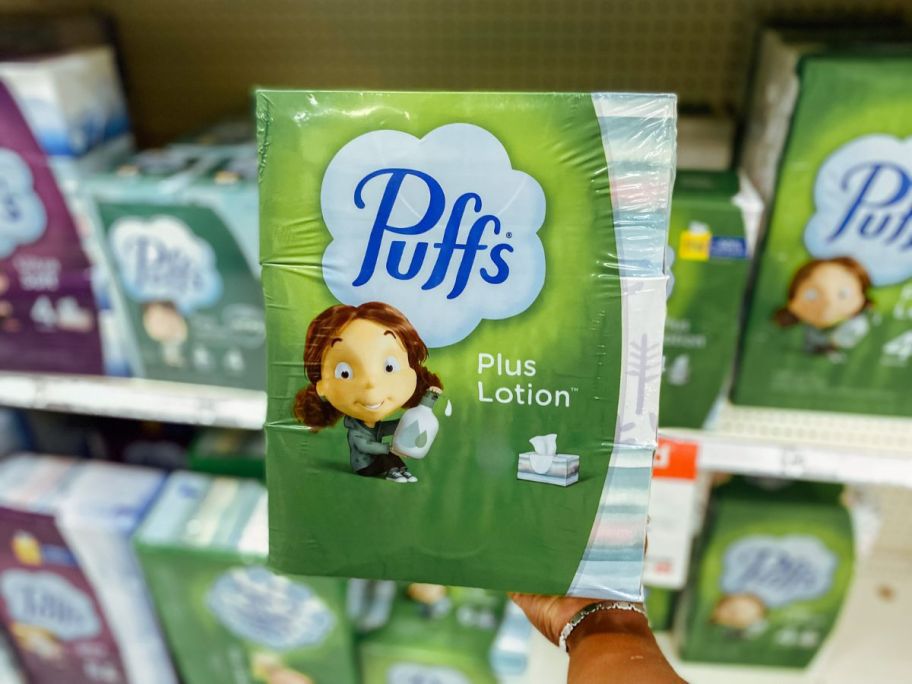 Puffs Plus Lotion Tissues package being held by hand in store