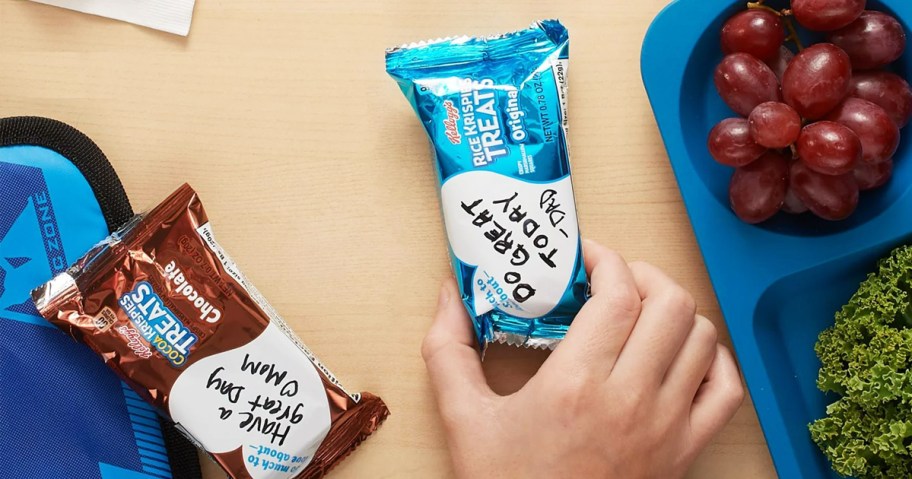 hand grabbing Rice Krispies Treat from table near lunch box