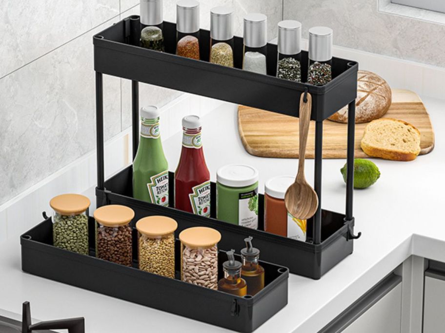 Spacekeeper 3-Tier Slim Rolling Storage Cart in Black shelves on kitchen counter with condiments in it