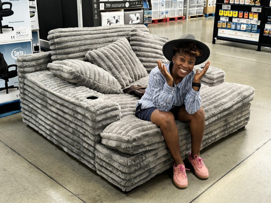 woman sitting on large grey lounge chair in store