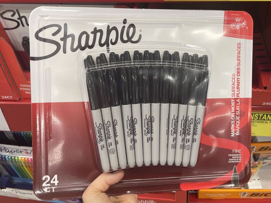 Hand holding up a 24-pack of Black Sharpie Markers