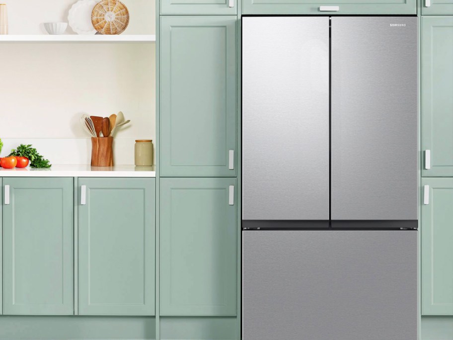 stainless steel french door fridge in kitchen with green cabinets