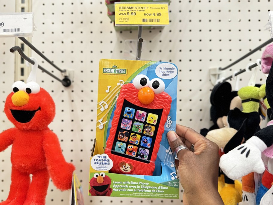 hand grabbing Sesame Street Learn with Elmo Phone from store display wall