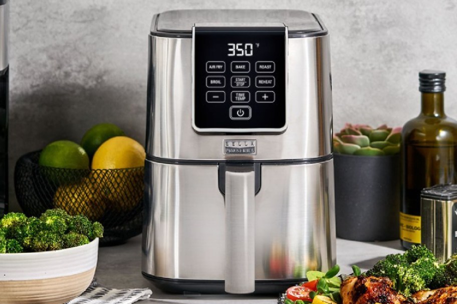 Silver airfryer with food displayed around it 