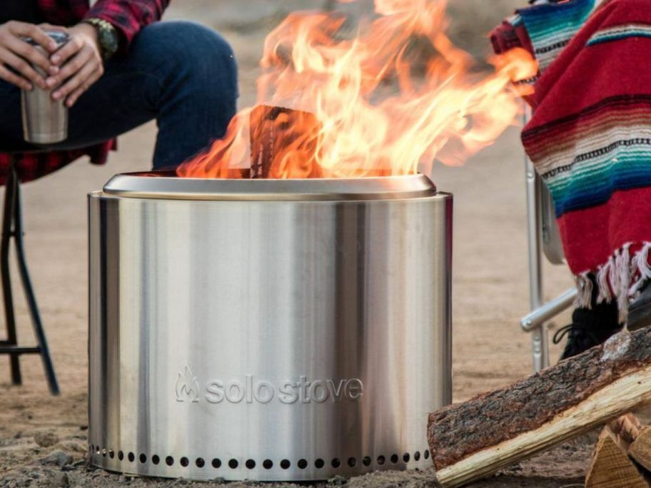 Solo Stove Bonfire Outdoor Stainless Steel Wood Burning Fire Pit with people sitting around it on a beach