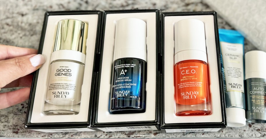 hand touching 3 boxed Sunday Riley Serums