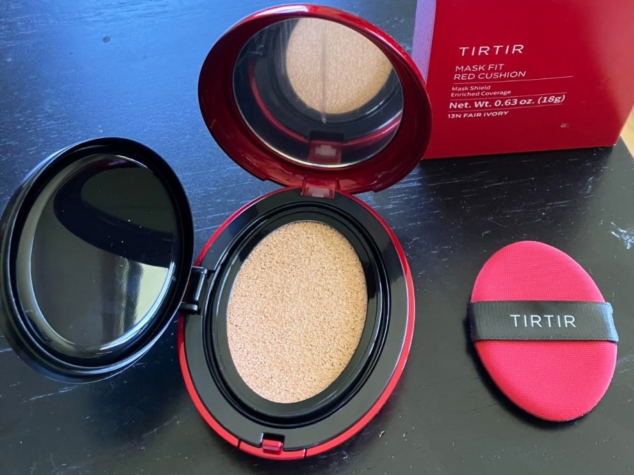 opened red and black compact of powder foundation on table