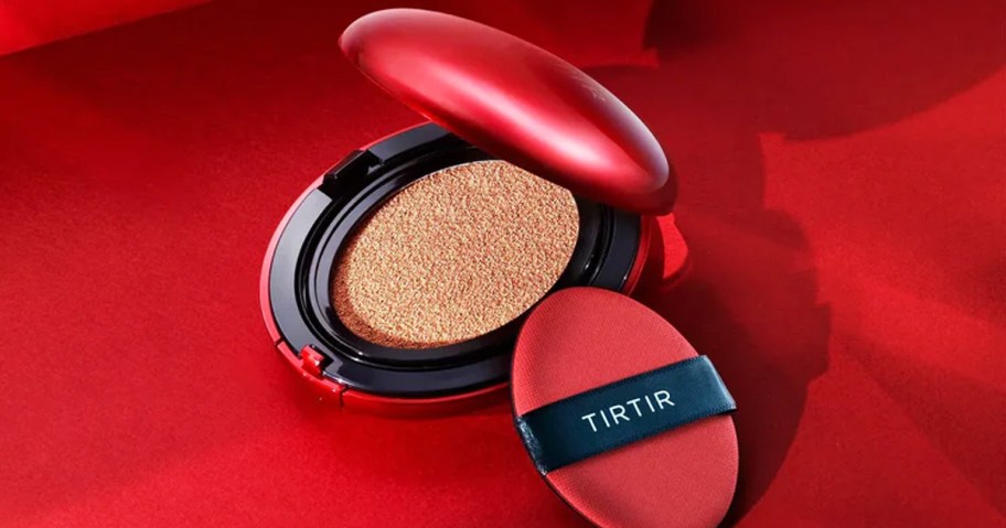 opened red and black compact of powder foundation with red sponge