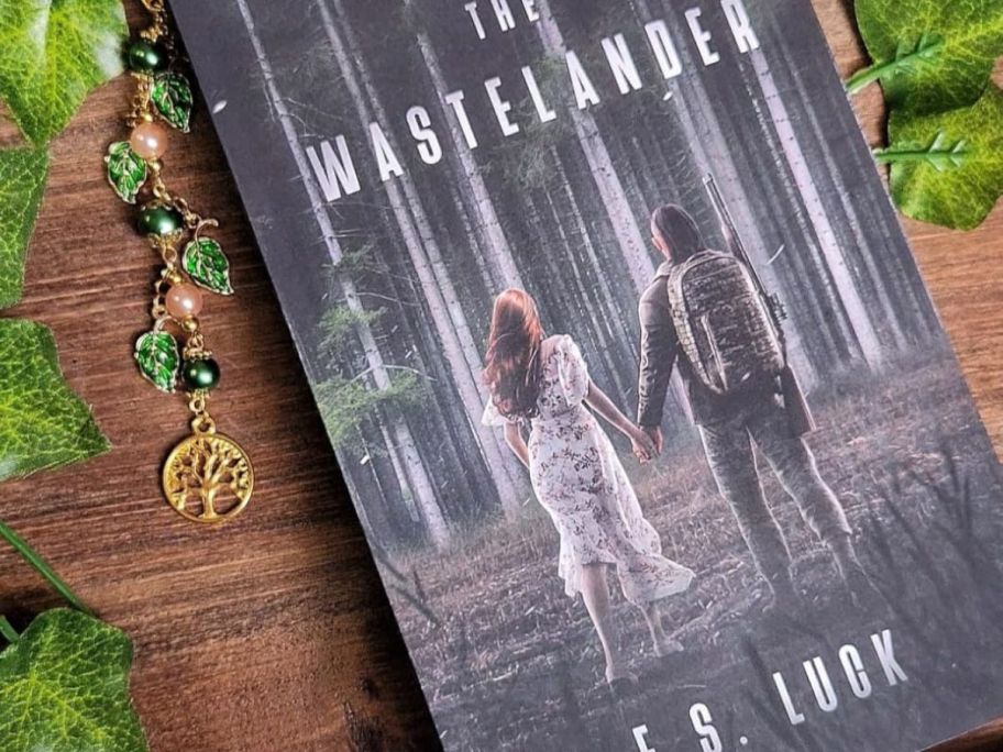The Wastelander book on a wood table surrounded by Ivy leaves