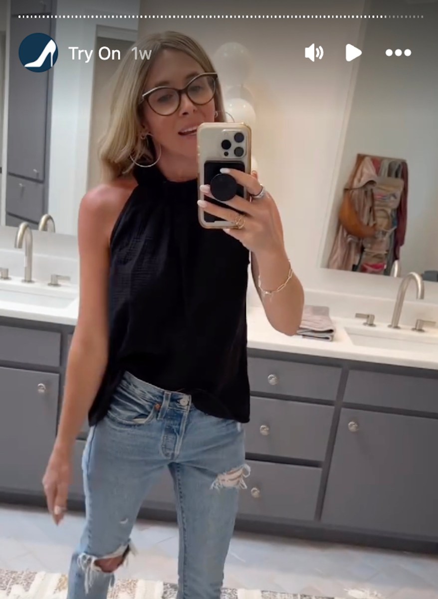 woman posing in bathroom with black halter top and ripped jeans on instagram stories