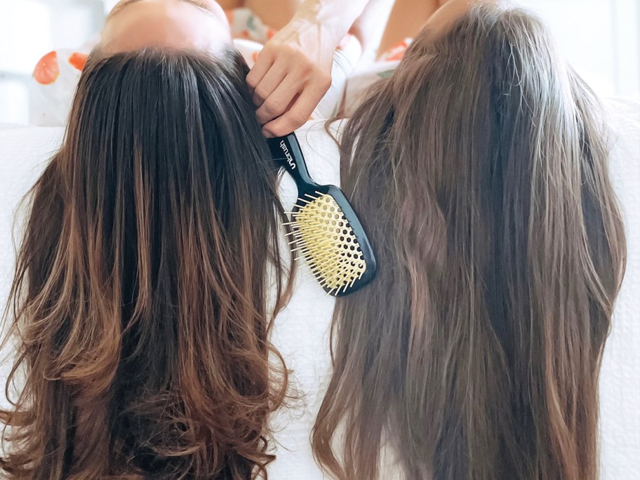 two women with long brown hair holding unbrush hairbrush 