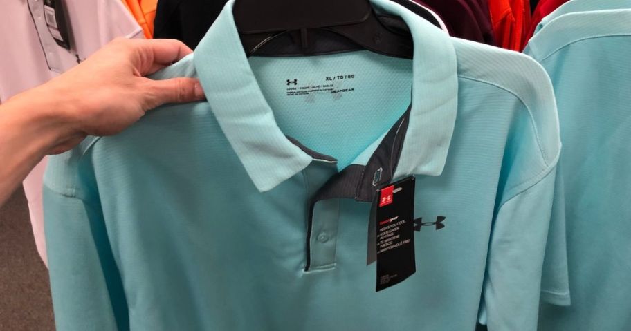 hand holding up an under armour polo on a hanger