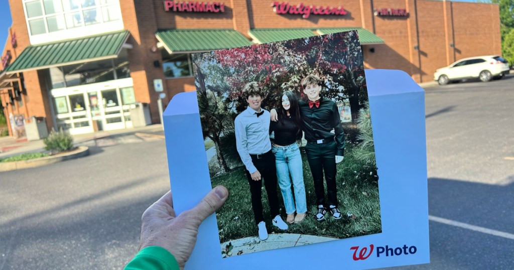 woman holding up 8x10 photo print outside walgreens