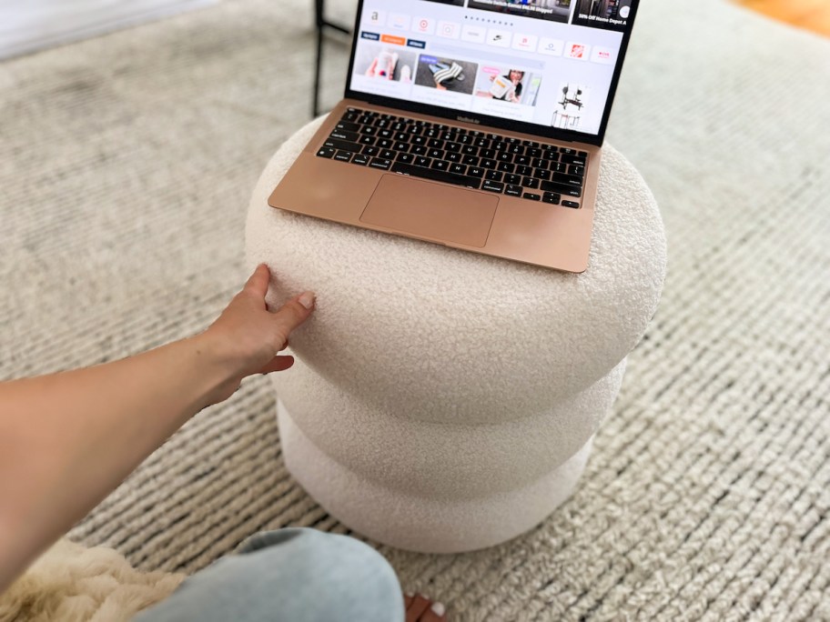 hand touching side of white cloud shaped ottoman with laptop on top