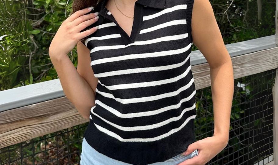 a woman wearing a black and white striped sweater vest