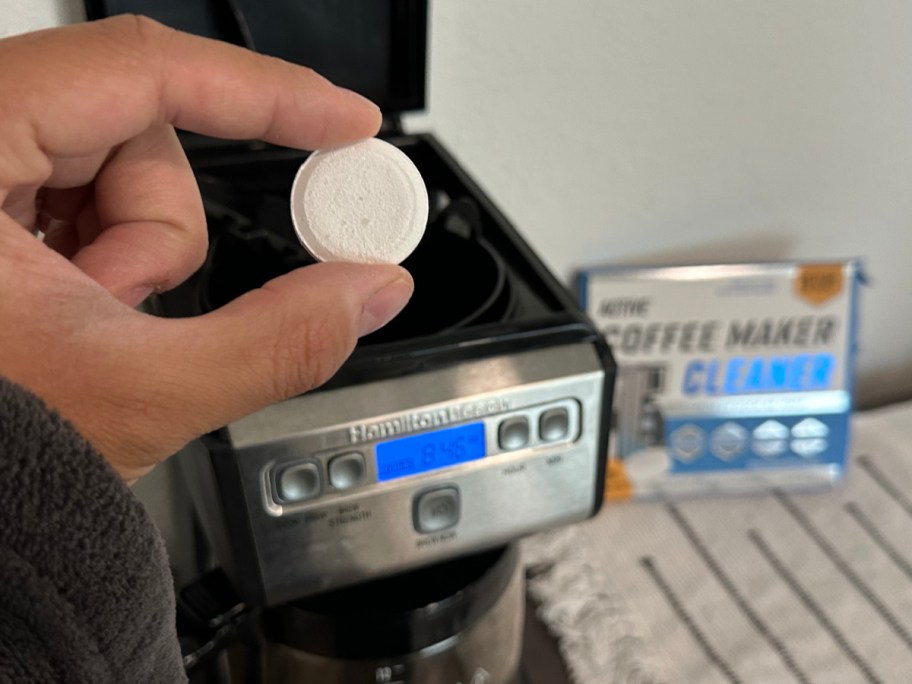 hand dropping active coffee cleaner tablets into brewer