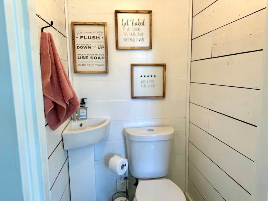 small half bath with corner sink and funny wall art