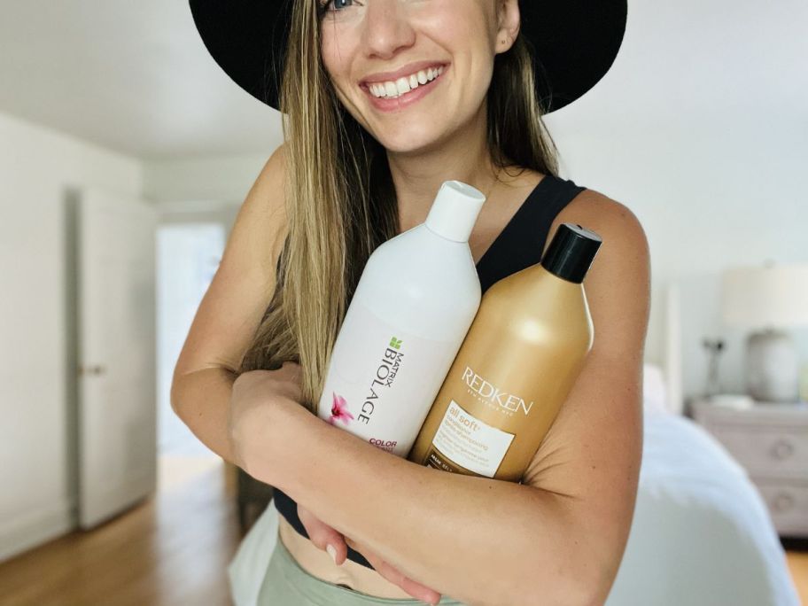 woman holding shampoo and conditioner liters in her arms