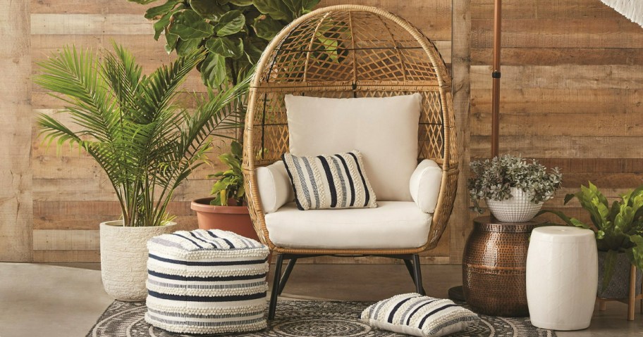 brown wicker egg chair with white and black pillows on patio