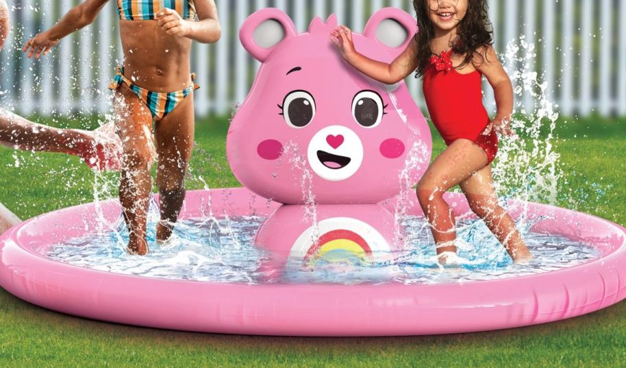 two little girls playing on a care bears splash pad