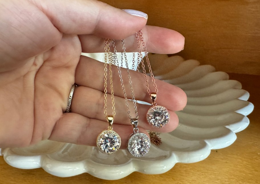 hand holding three pendant necklaces