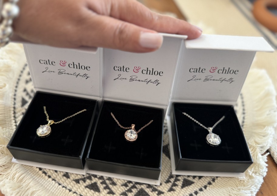 hand holding three necklaces in gift boxes