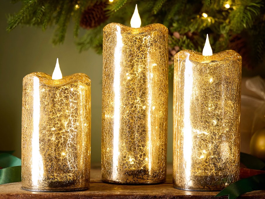 three gold crackle glass candles sitting on table 