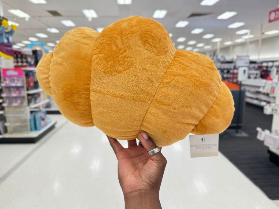 Bullseye's Playground croissant pillow being held by hand in store