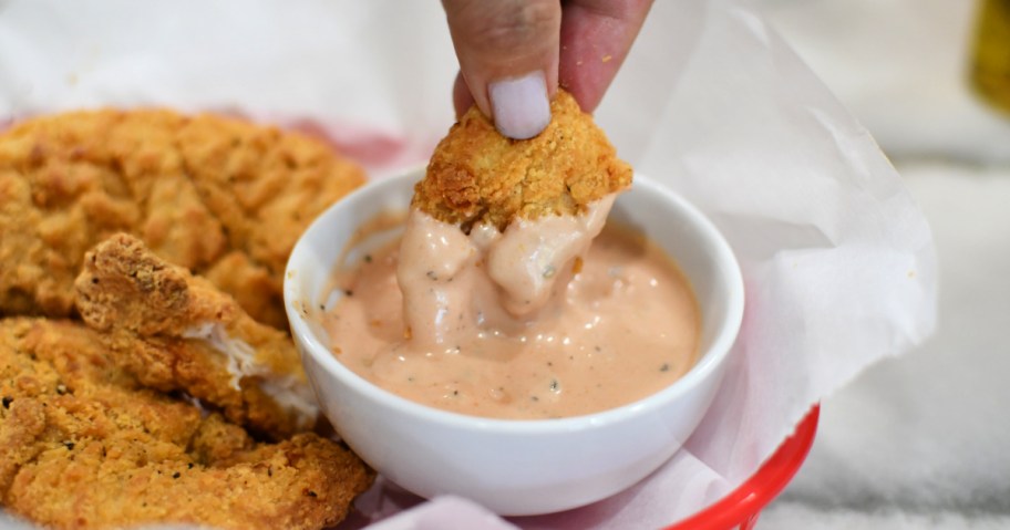 dipping chicken tenders into Cane's sauce