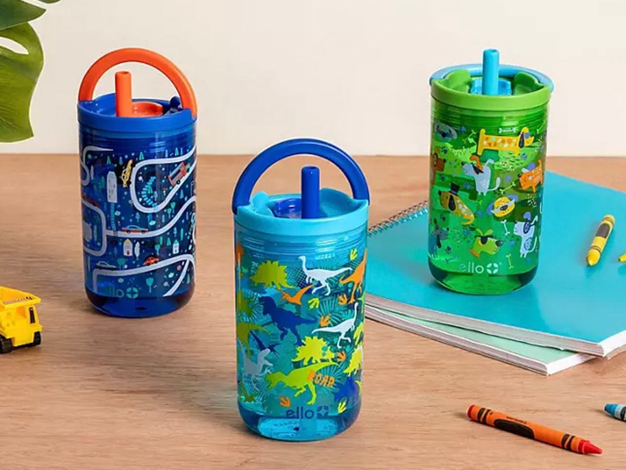 three blue and green ello tumblers with cars and dinosaurs on table 