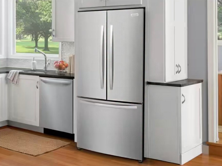 stainless steel refrigerator in kitchen with white cabinets