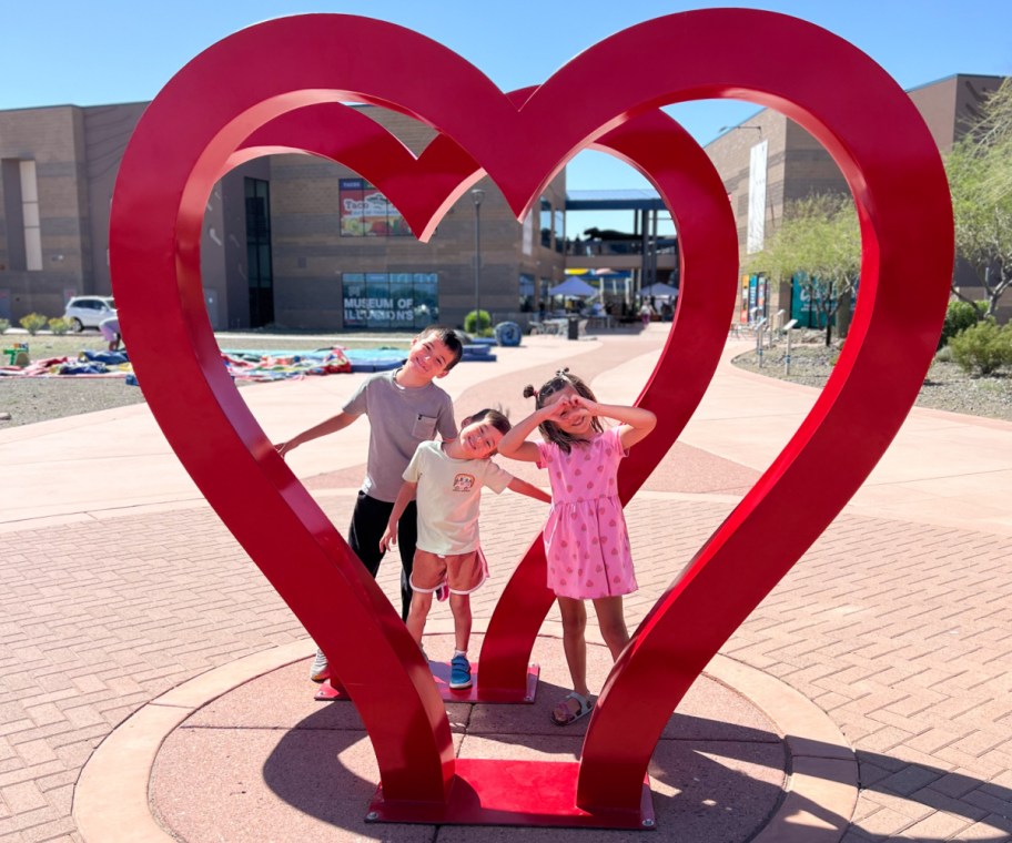 kids standing in heart sculpture