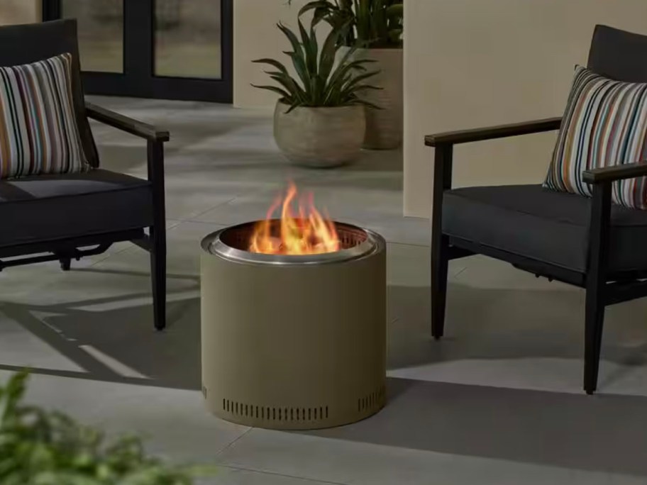 green firepit outdoors next to two chairs