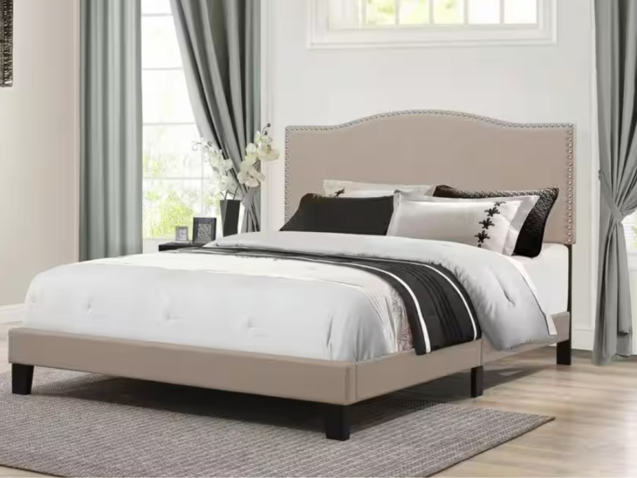 tan platform bed frame with mattress and comforter, pillows in a bedroom