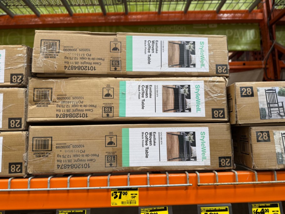 Three stacked cardboard boxes for StyleWell Eastlake Woven Coffee Tables on an orange store shelf above a yellow $37.00 clearance tag.
