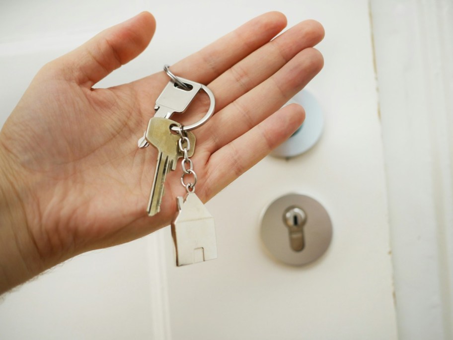 hand holding a set of house keys in front of door to investment property