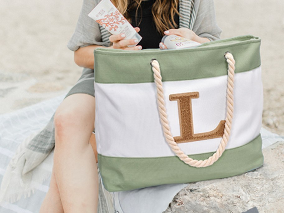 woman putting products into L initial beach tote 