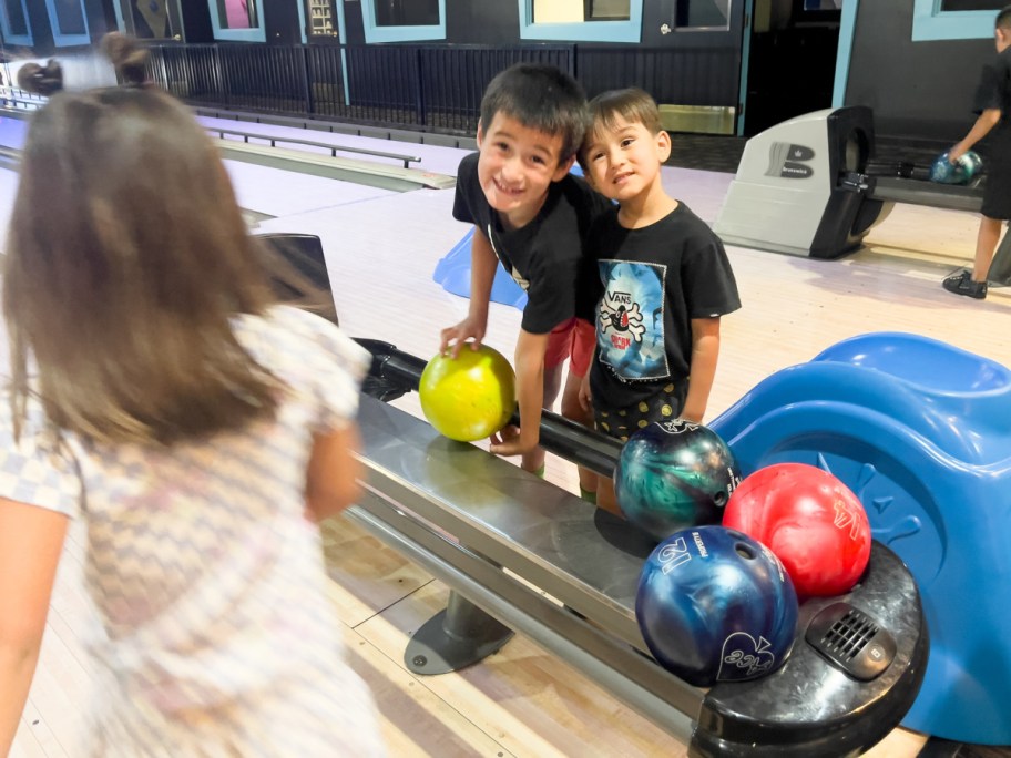kids playing with bowling ball at bowling place