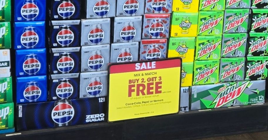 stacks of soda 12 packs with a by 2 get 3 free sale sign in front of them in store