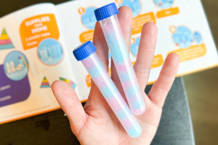 two test tubes in hand with pink and blue colors