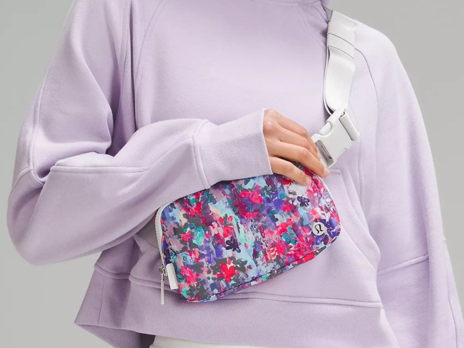 woman wearing a light purple shirt with a multicolor lululemon belt bag