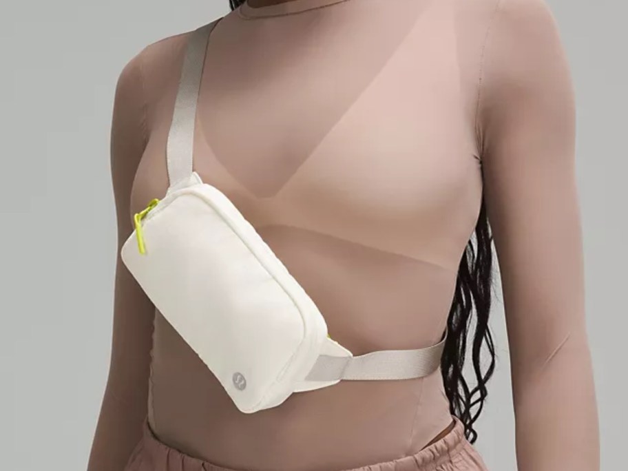 woman wearing a tan shirt with a cream lululemon mini belt bag