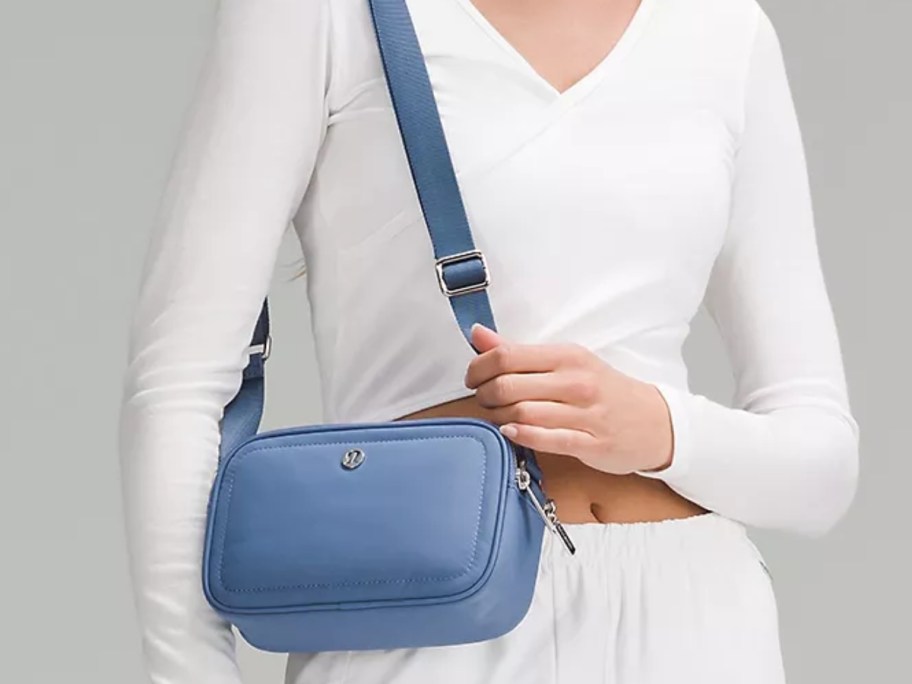 woman waring a white vneck top and shorts carrying a light blue lululemon purse